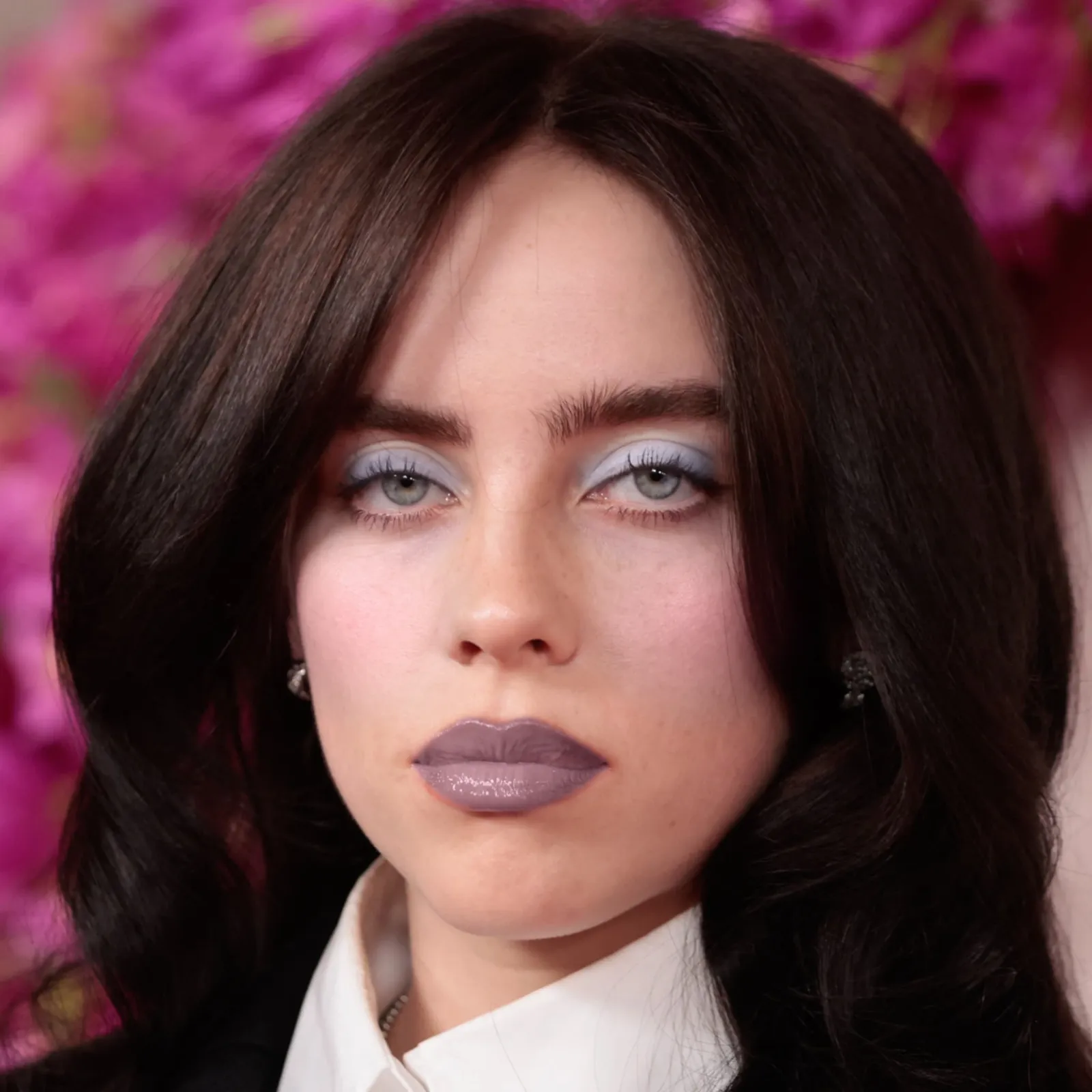 Billie Eilish with cool makeup — icy blue shadow and deep mauve lip